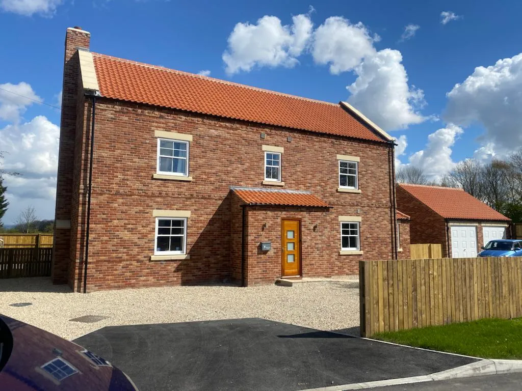 A brick house with a wooden fence in front of it.